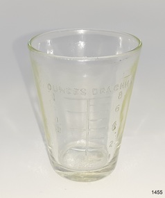 Clear glass with inward sloping sides and embossed inscriptions
