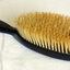 Brown ebony handle and oval -shaped back with bristles.