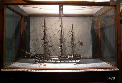 Shim model is in timber framed glass case with sign across the lower front