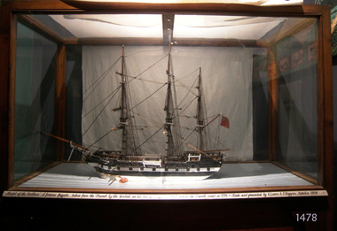 Shim model is in timber framed glass case with sign across the lower front