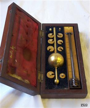 Brass hydrometer with eight weights and accompanying thermometer, in an open wooden box