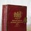 Small red hard covered book, embossed gold text and logo on front, brass clasp across opening