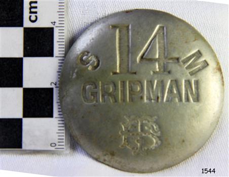 Front of metal badge has stamped text and logo