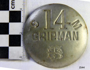 Front of metal badge has stamped text and logo