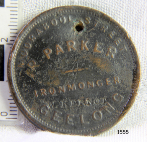 Round medallion with embossed inscription and design, and a formed hole