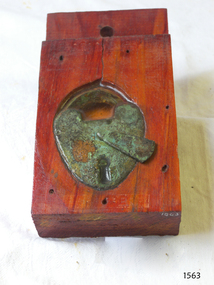 Padlock is embedded in a block o timber and sealed with resin