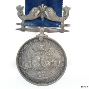 Silver metal hangs from a silver bar with a fleur de lies between two fish. Text surrounds a variety of images.