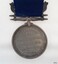 Inscription around edge of medal, surrounds inscription in centre