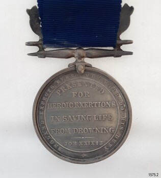 Inscription around edge of medal, surrounds inscription in centre