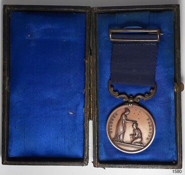 Case is hinged in centre and is lined in blue fabric with a sheen. Medal on left side is showing front surface.