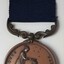 Medal has a silver bar pin, blue ribbon and bronze medal with two figures on front