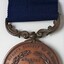 Medal has printed lettering and wreath, enclosing engraved details of recipient and date