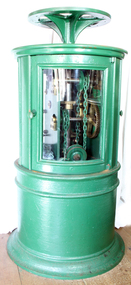 Round green metal cabinet with a wheel on top, glass doors, and mechanical equipment inside.