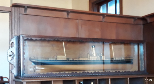 Glass fronted case has decorative border and carved wooden side decoration