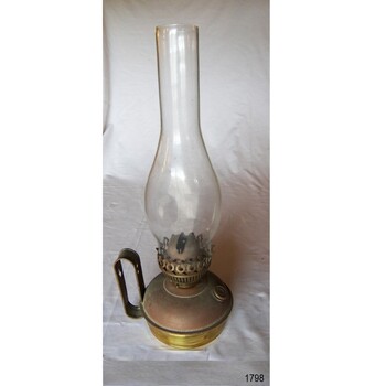 Brass lamp with glass flame cover over burner, and brass tank with a handle