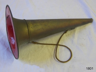 Conical brass object with opening at both ends; the wide end has a rim and is painted red