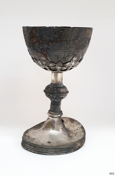 Base of chalice has a decorative border. It is buckeld