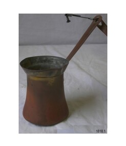 Metal cylinder with flared out top and flared out base, with a long diagonal handle