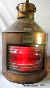 Brass and glass lamp with red coloured lens and brass plates with inscriptions