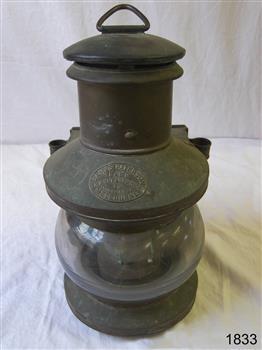 Round metal lamp with glass lens, hanging hook and maker's plate