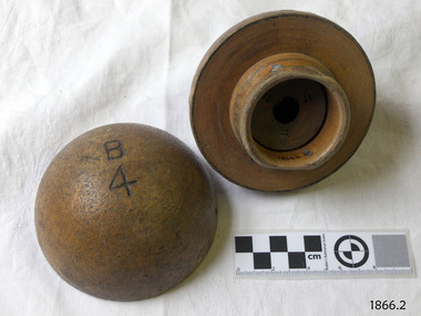 Two halves of a hollow wooden ball that has a peg and slot type join