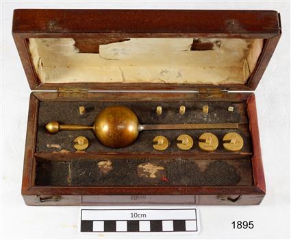 Open rectangular wooden case with brass weights and instruments inside