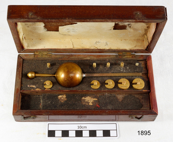 Open rectangular wooden case with brass weights and instruments inside
