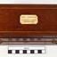 Polished wooden case has a plaque with inscription on the lid within a border