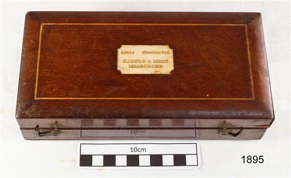 Polished wooden case has a plaque with inscription on the lid within a border
