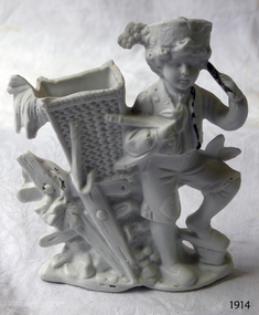 White male child figure wearing a hat, standing beside a woven basket