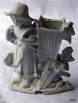 White ornament of girl wearing a hat and carrying a basket on her back