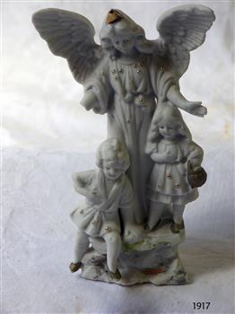 White porcelain ornament depicting an angel and two children; gold highlights