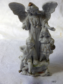 White porcelain ornament depicting an angel and two children; gold highlights