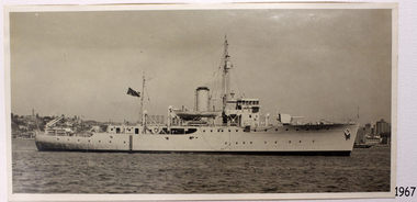 Steamship flying dark coloured flag with Union Jack and Star. Lifeboat suspended above centre of deck.