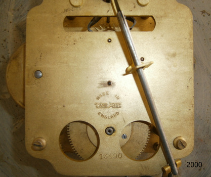 Inscriptions with text and numbers are stamped on the backplate of the clock mechanism