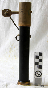 Cylinder with brass base. Cover over top, held in place by a peg through the case, attached by string..