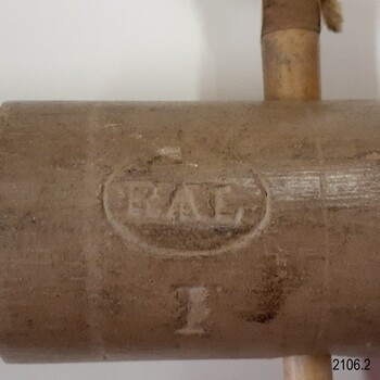 Oval with letters and symbol between the letters, impressed on cap