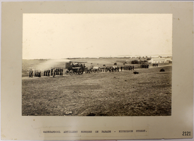 Group of military personnel with several cannon being pulled by a steam driven carriage.