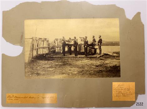 Photograph in sepia depicts military figures beside a cannon.