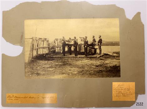 Photograph in sepia depicts military figures beside a cannon.