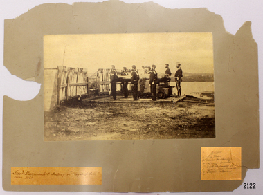 Photograph in sepia depicts military figures beside a cannon.