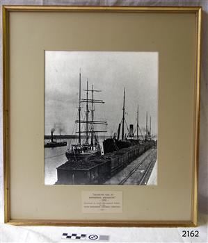 Black and white photograph of shps and tram containers of coal at a jetty
