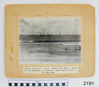 Black and white photograph mounted on cream card. Handwritten and printed labels. Subject is vessels in the sea with a wreck close to shore in the foreground 