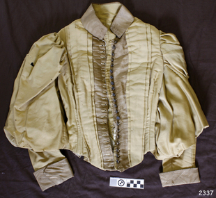 Gold bodice with brown collar, cuffs and front placket. Sleeves are leg-of-mutton style. 