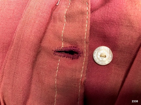 Close up view of hand stitched buttonhole and button from ladies bodice.