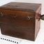 The lid has swinging hook closures at the front. Leather carry strap attached to the sides.