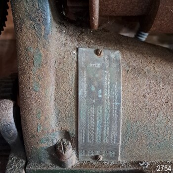 Rectangular metal plate with characters, screwed onto machine