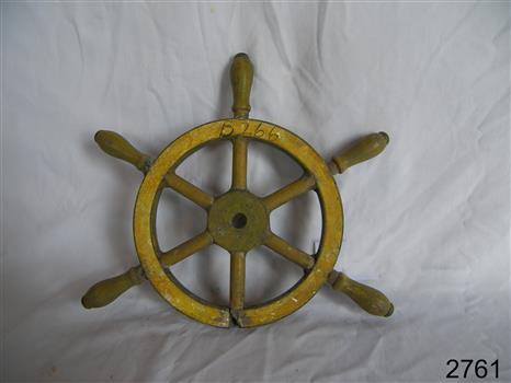Wooden ship's wheel with six spokes and an inscription in black pen