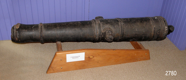 Iron cannon mounted horizontally on a wooden frame