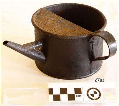 A slightly rusty metal ink kettle or jug with a spout, and a handle on the side.